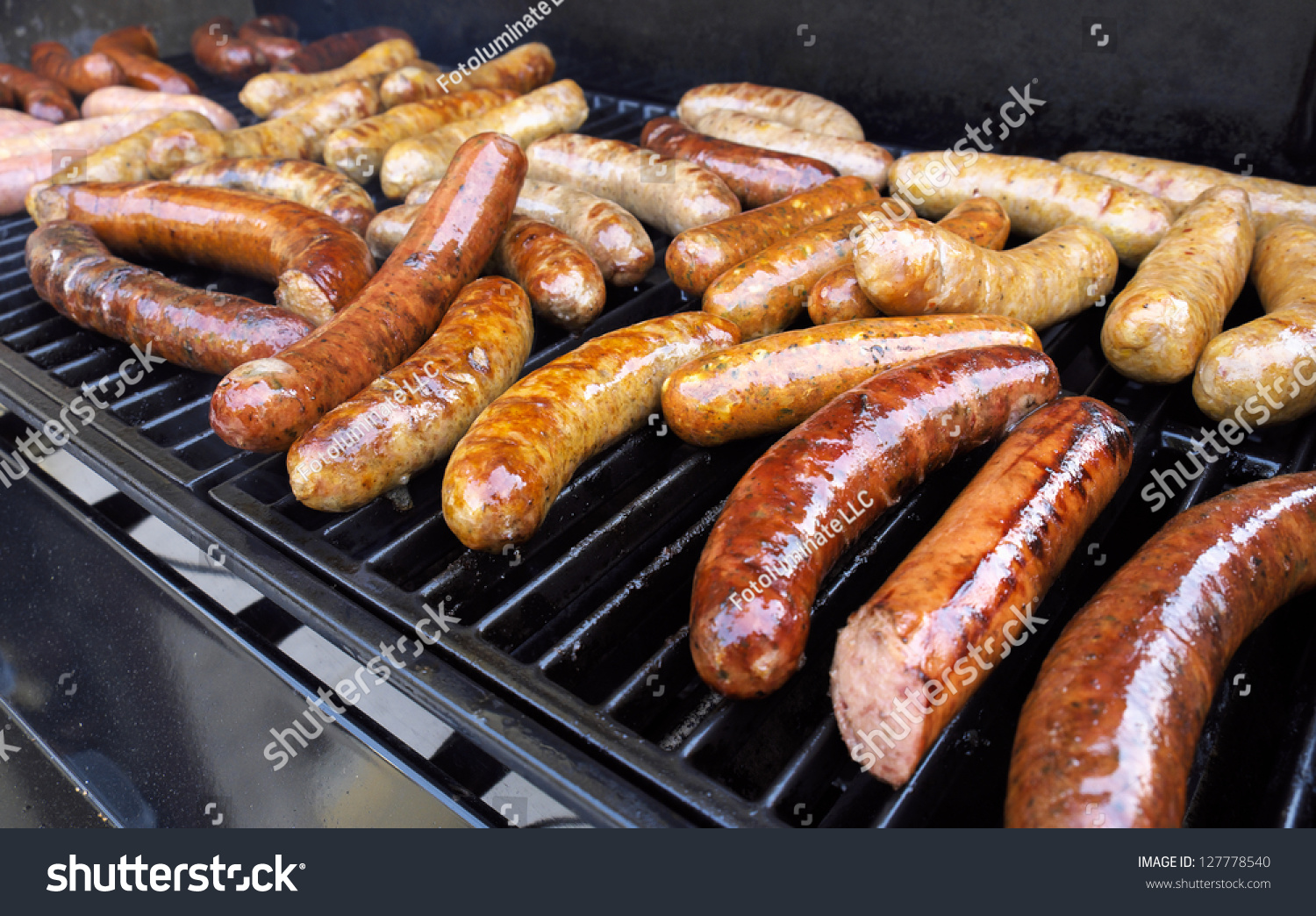 Fresh sausage and hot dogs grilling outdoors on a gas barbecue grill. #127778540