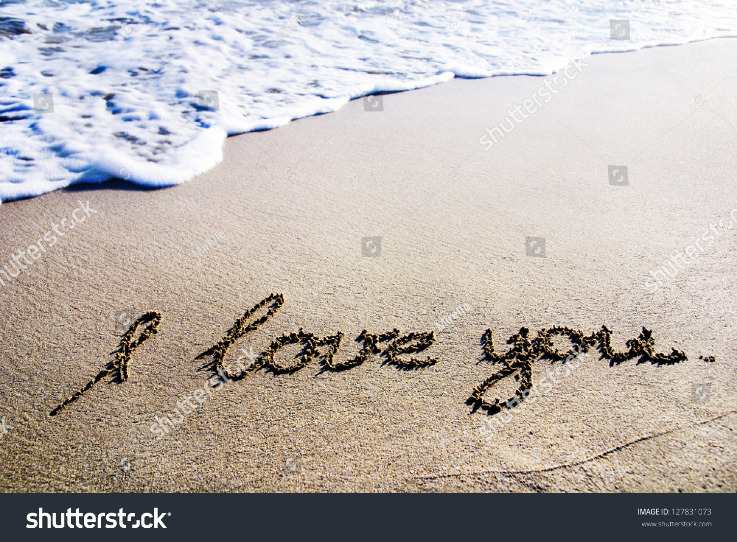 words "I love you" outline on the wet sand with the wave brilliance #127831073