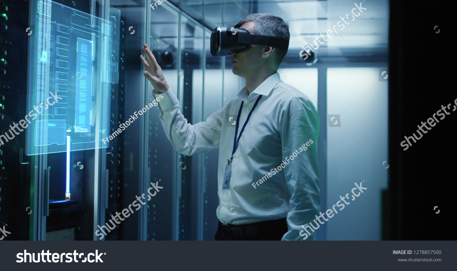 Medium shot of a male technician in VR glasses using two virtual interfaces while working in a data center #1278857500
