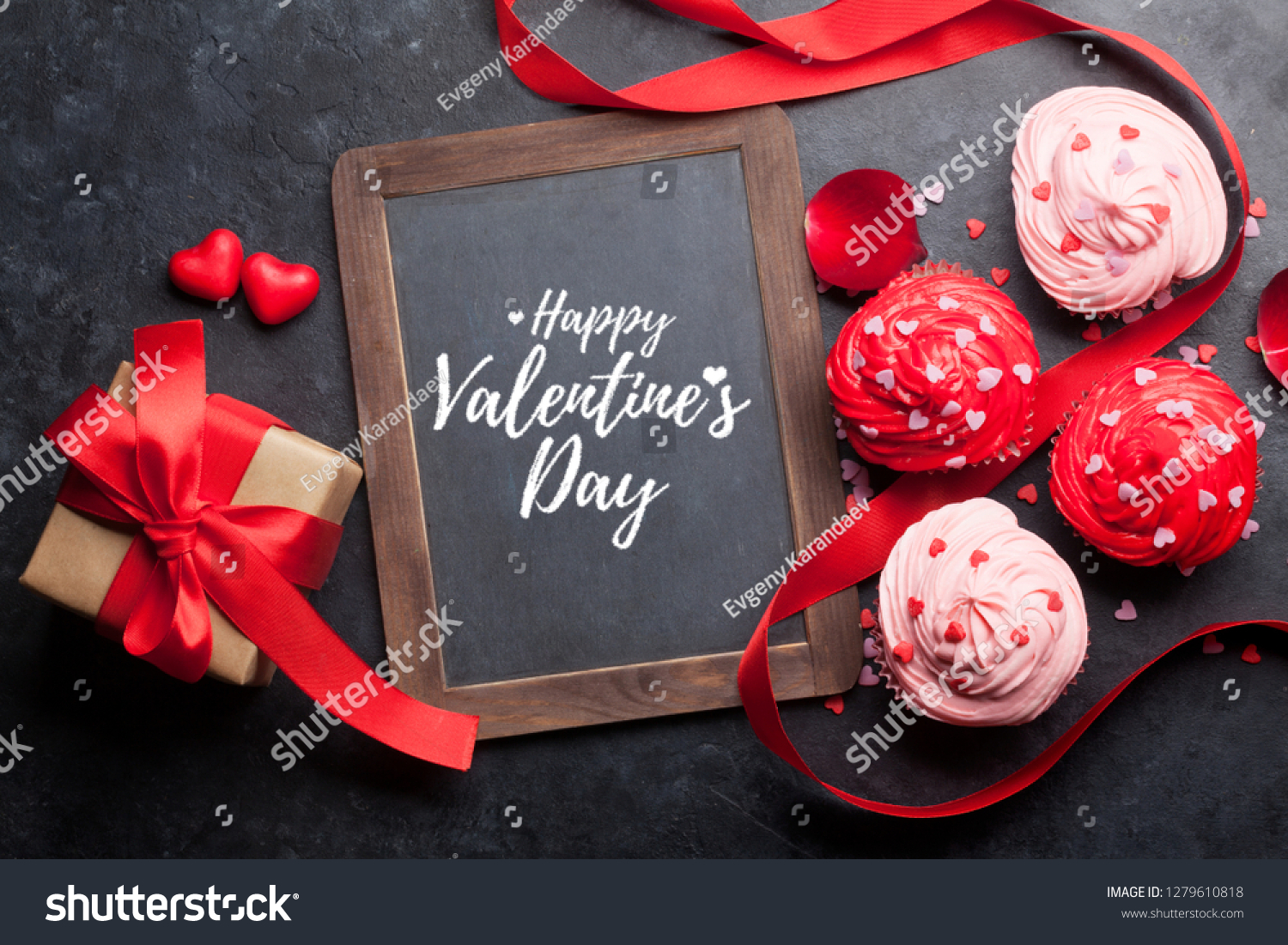 Valentine's day greeting card with delicious sweet cupcakes and gift box on stone background. Top view #1279610818