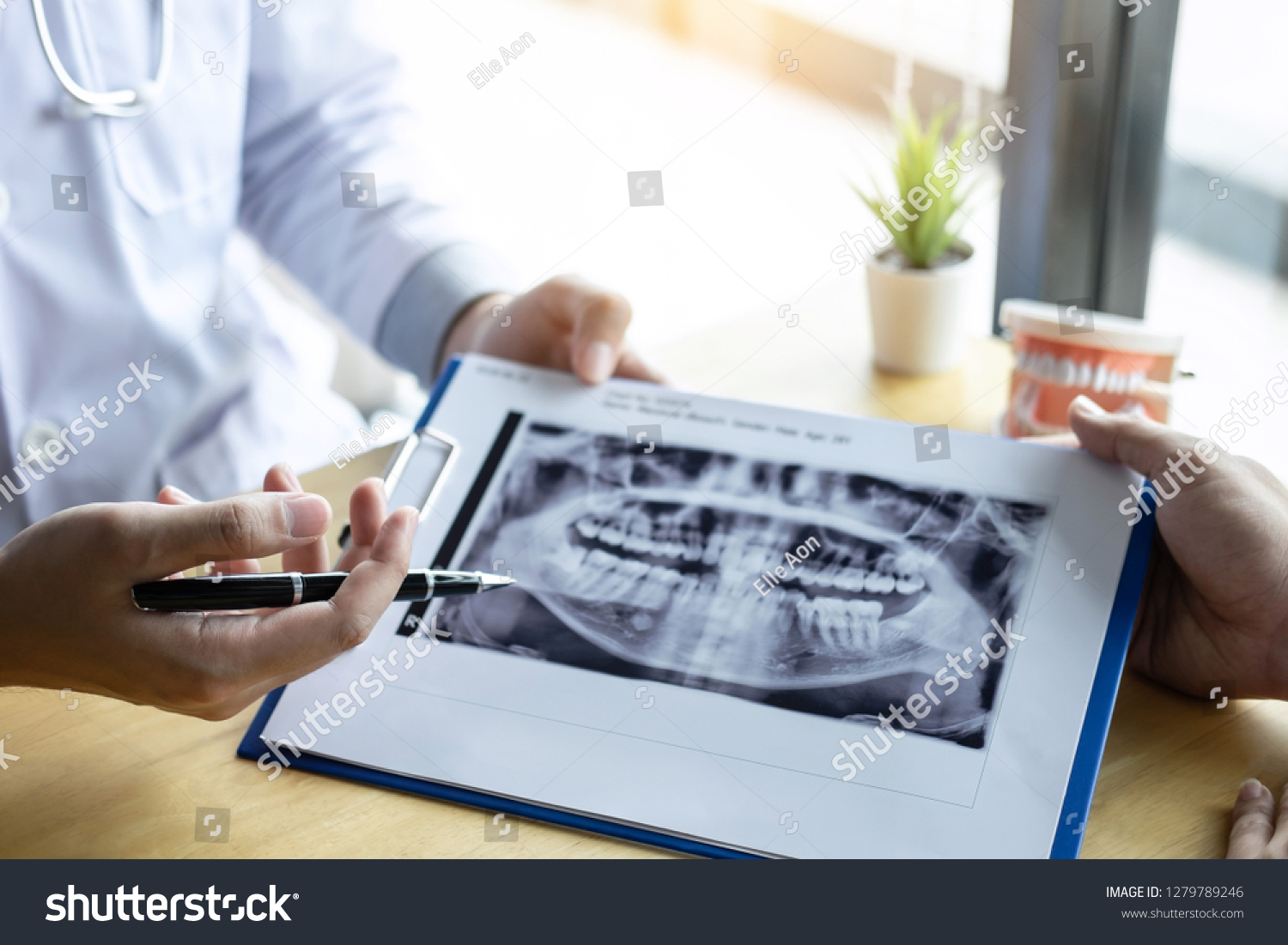 Image of doctor or dentist presenting with tooth x-ray film recommend patient in the treatment of dental and dentistry, working at workplace. #1279789246