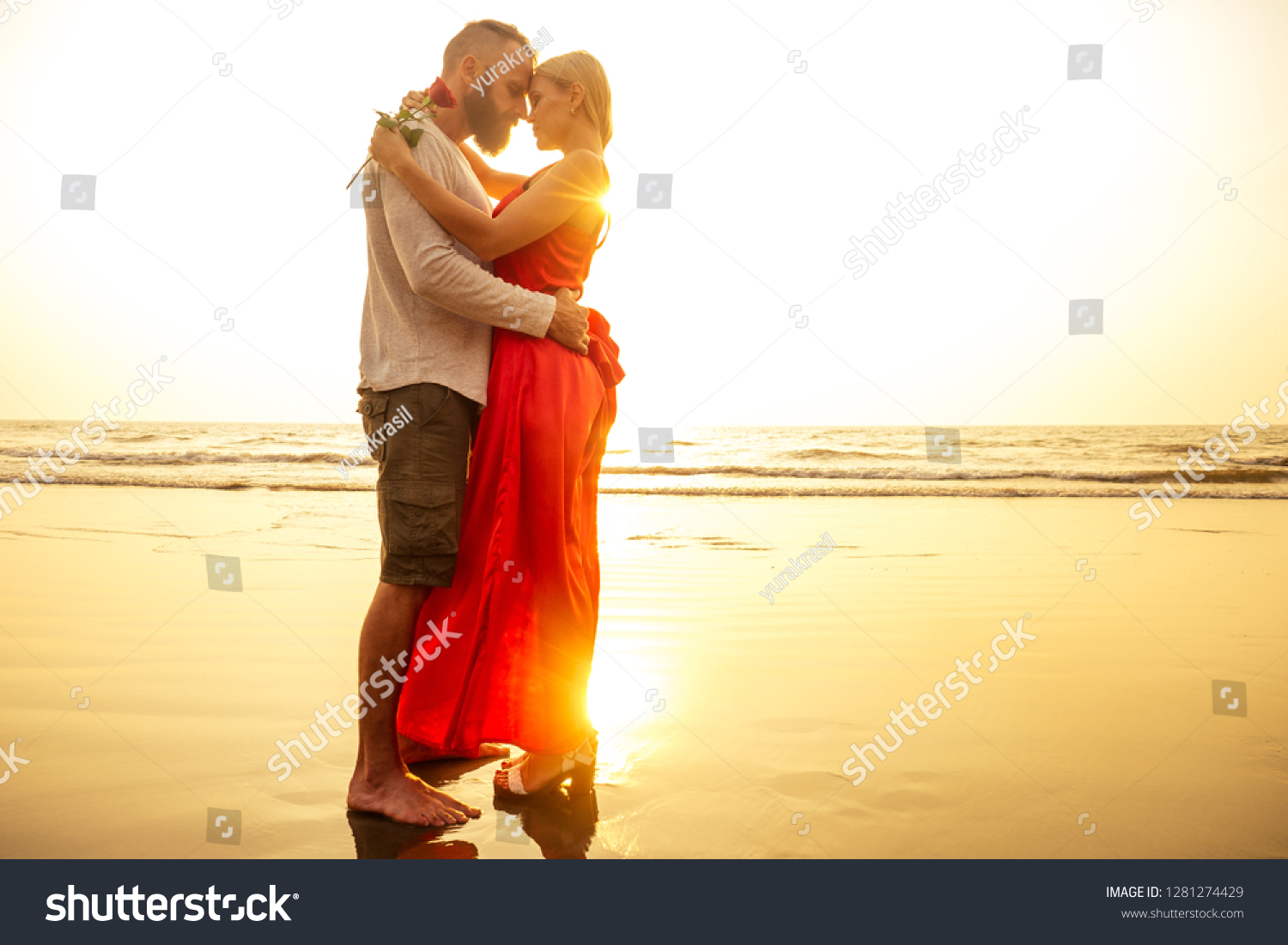 two lovers people at sunset by the sea romance and tenderness feelings first love date.man and woman blonde in a dress on the beach with a rose sun rays.Valentine's day and International Women's Day #1281274429