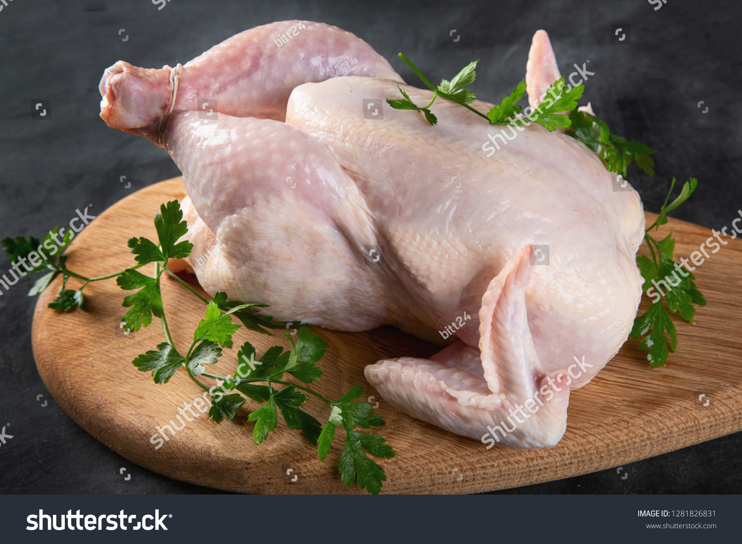 Whole raw chicken with seasonings on wooden cutting board on black background #1281826831
