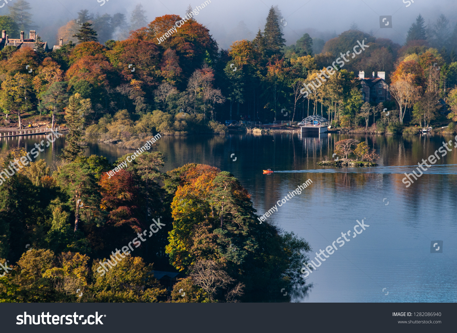 Cloud over Derwent Water lake in the Lake District Cumbria with Autumn colours and view of boathouse in the clear water. #1282086940