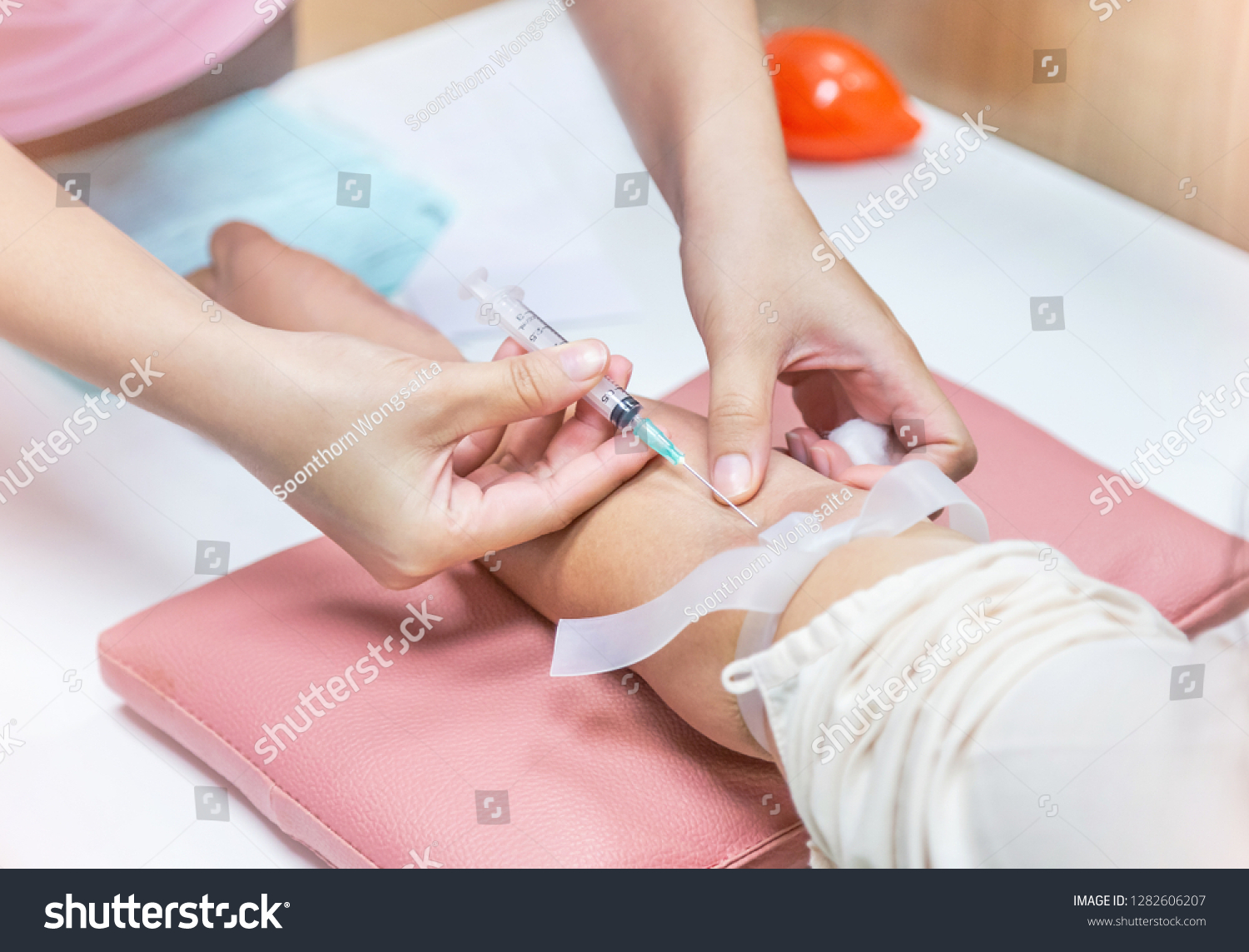 Nurse injecting with syringe to patient's arm drawing blood sample for blood test in hospital #1282606207