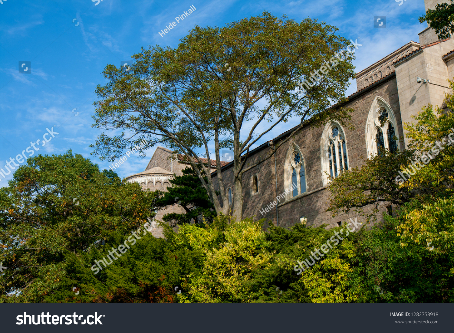 New York, USA - October 12, 2010: scenic view of a facade with gothic bows of the Cloisters in Tryon Park on a sunny day with deep blue sky and idyllic trees #1282753918