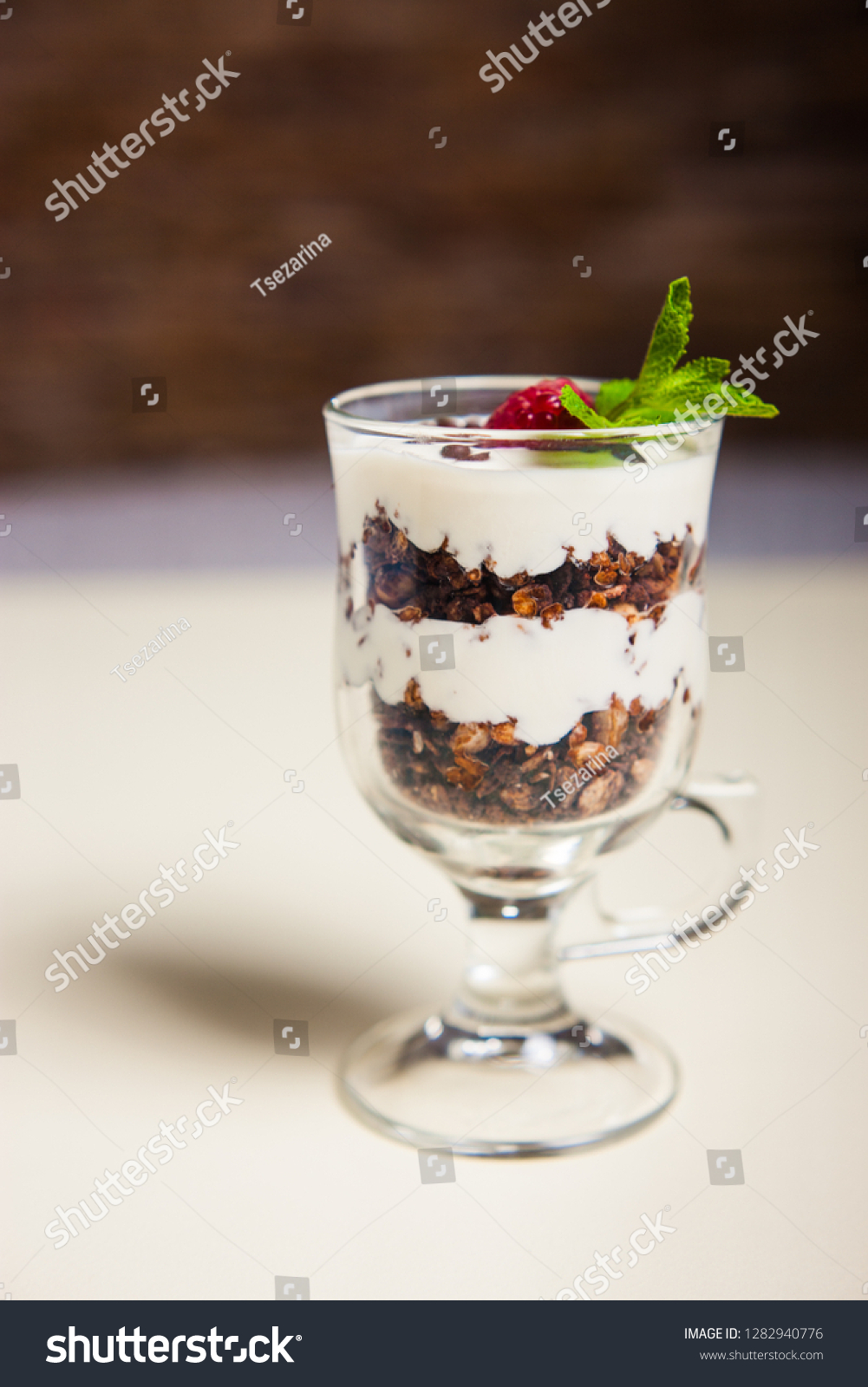 Yogurt with cream, strawberry and muesli served in glass on the table #1282940776