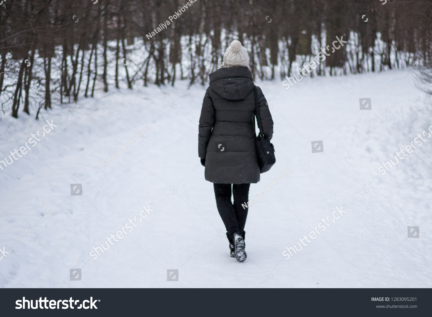 Back view of lonely girl walking on the road of snow in winter park. Silhoette of person. Period of depression and search of life meaning. #1283095201