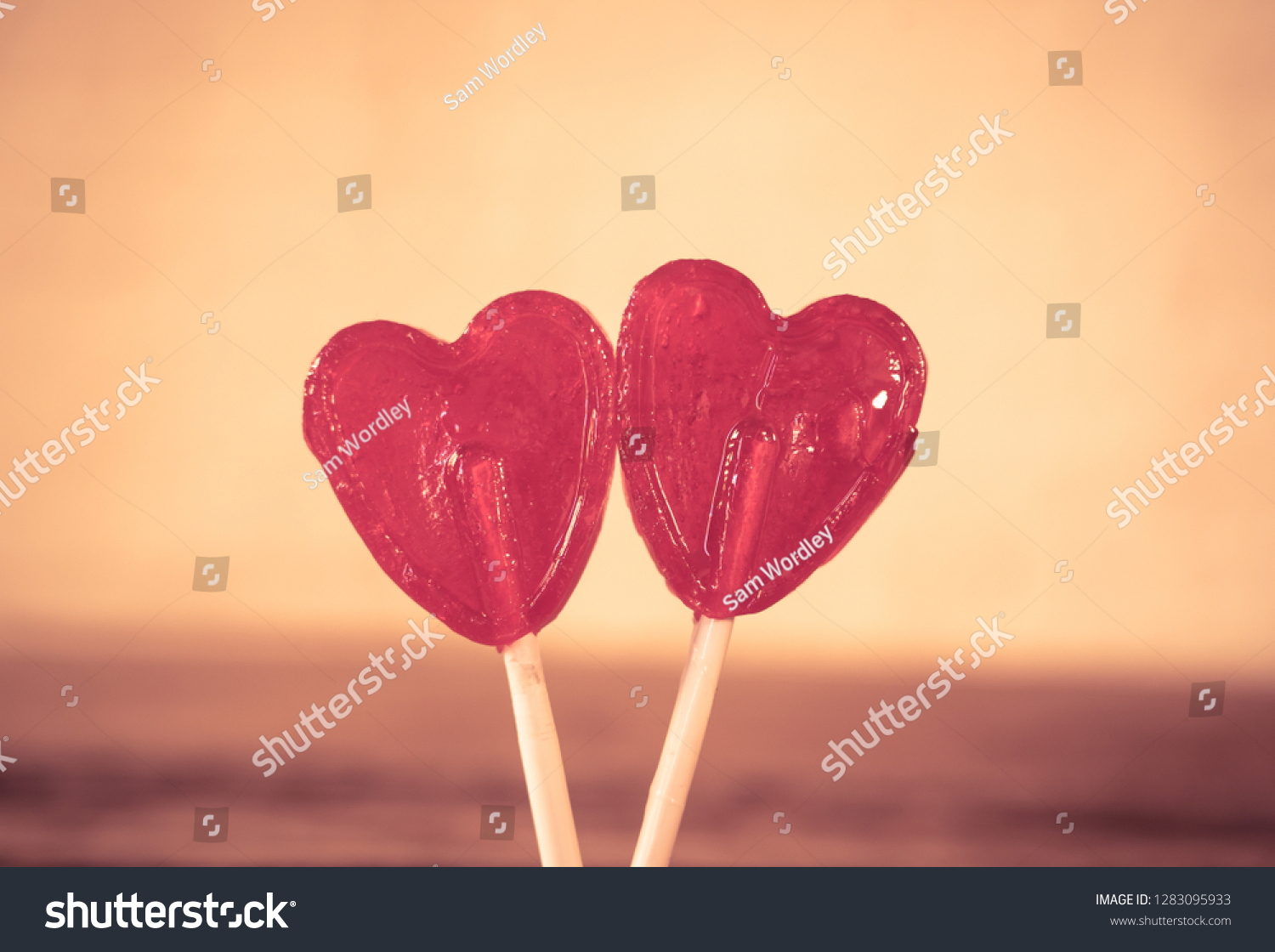 Two cute red heart shaped lollipops on rustic wooden table and beautiful romantic mood light and blur background as metaphor of love, togetherness and Valentines day greetings car design concept. #1283095933