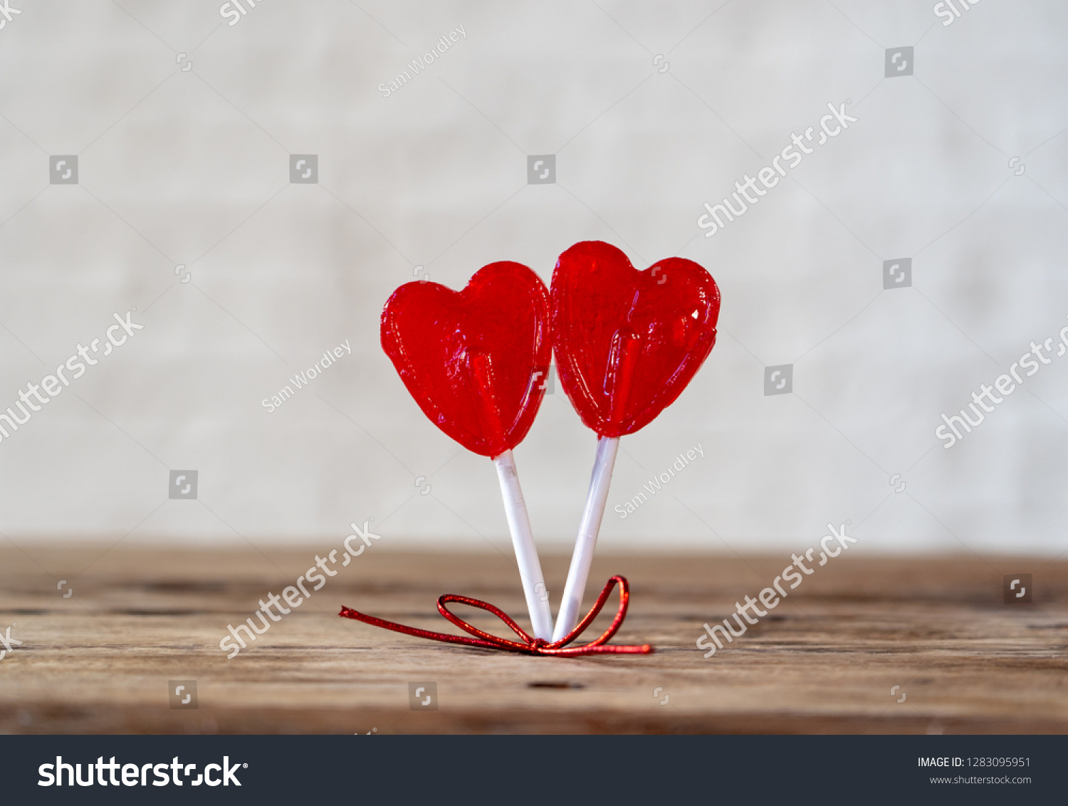 Two cute red heart shaped lollipops on rustic wooden table and beautiful romantic mood light and blur background as metaphor of love, togetherness and Valentines day greetings car design concept. #1283095951
