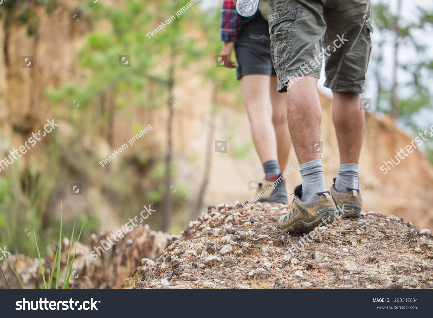  Group of man and women are walking trough forest path wearing mountain boots and walking sticks. Low section view. #1283347084