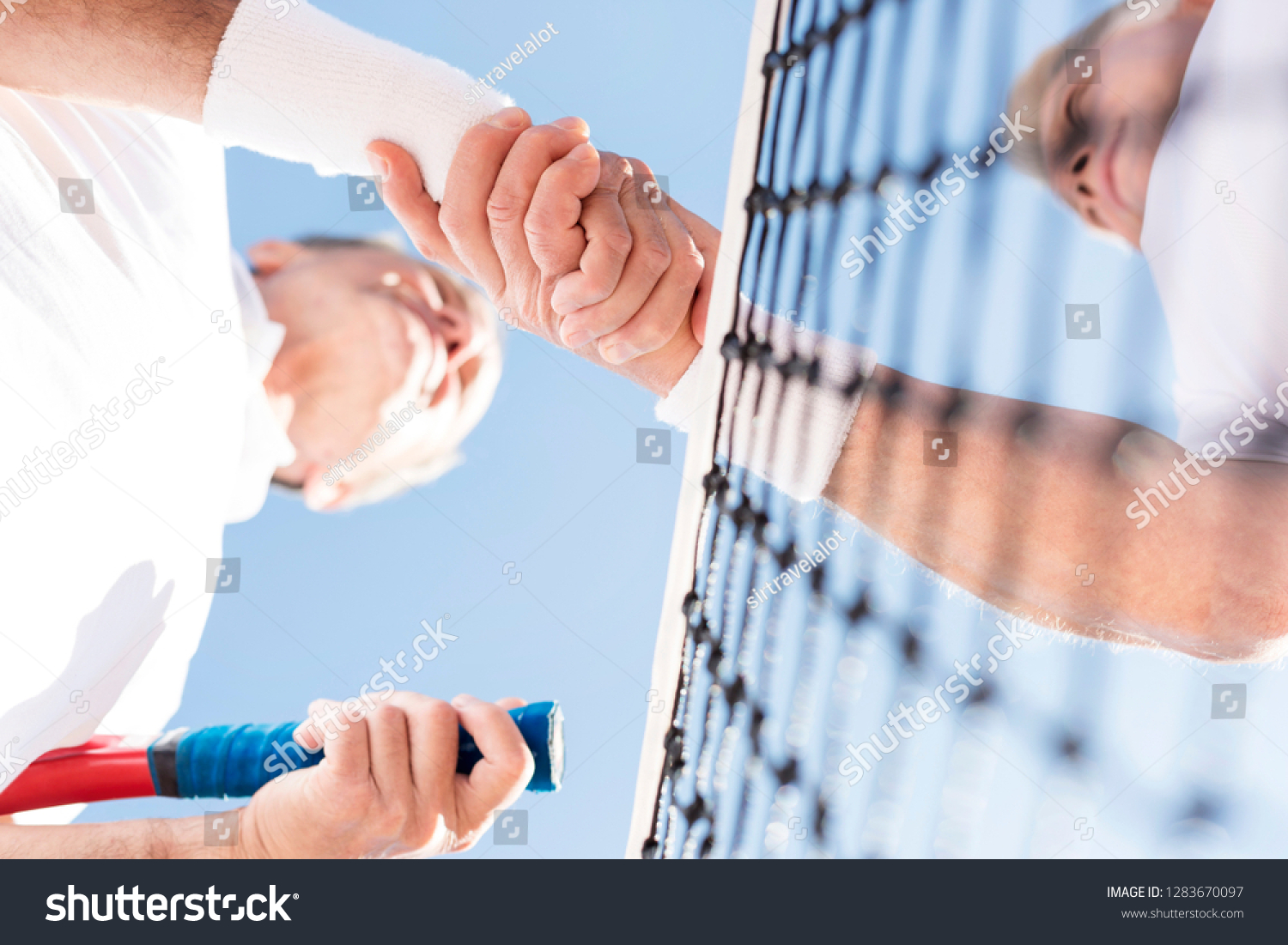 Directly below view of men greeting while standing against clear sky during match on sunny day #1283670097