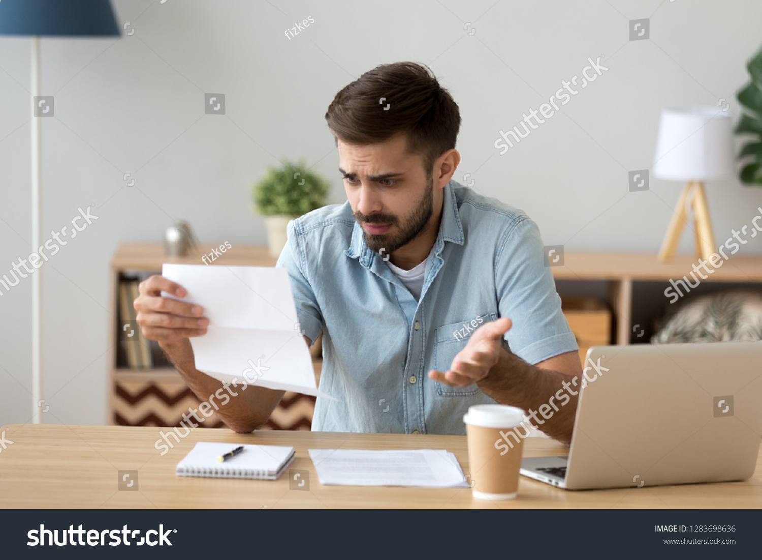 Confused frustrated young man holding mail letter reading shocking unexpected news nonsense in paper document, mad about high bill tax invoice, debt notification, bad financial report, money problem #1283698636