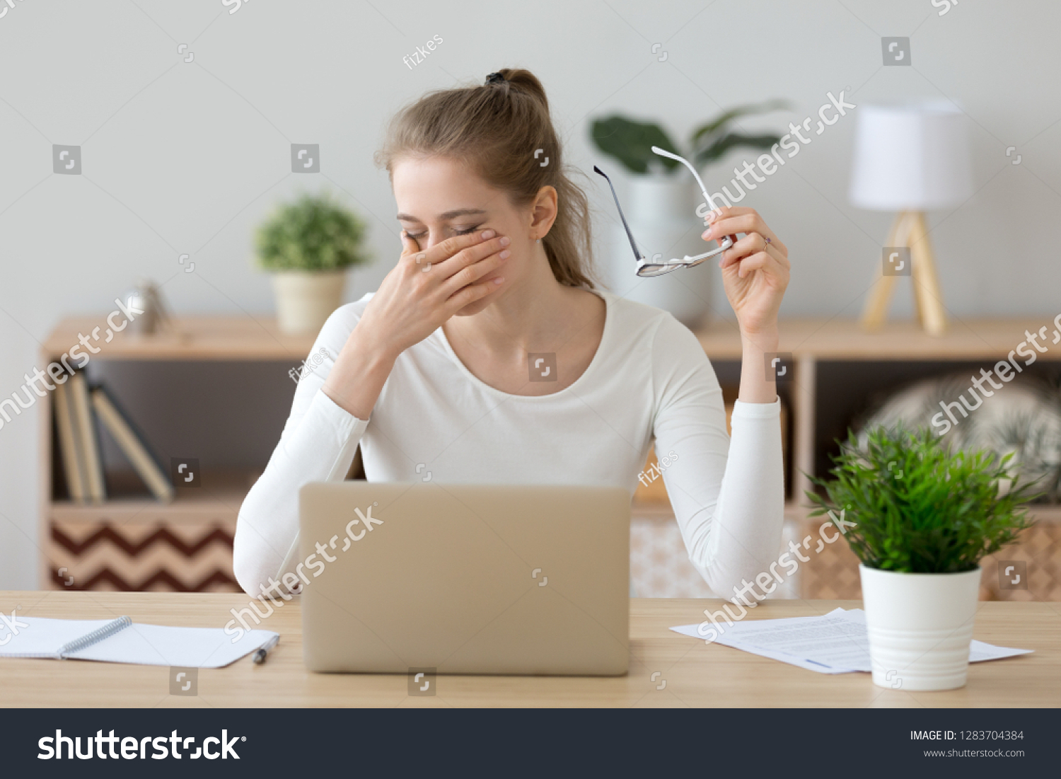 Tired young woman student feeling eye strain bad blurry vision rubbing dry irritated eyes taking off glasses after computer work, fatigued teen girl suffer from discomfort tension problem concept #1283704384