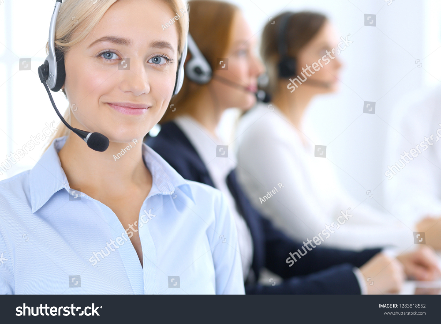 Call center. Group of operators at work. Focus at blonde business woman in headset #1283818552