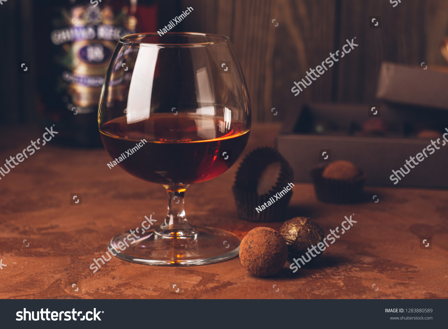 A glass of strong alcoholic drink brandy or brandy and a box of chocolates on a dark background. Copy space. #1283880589