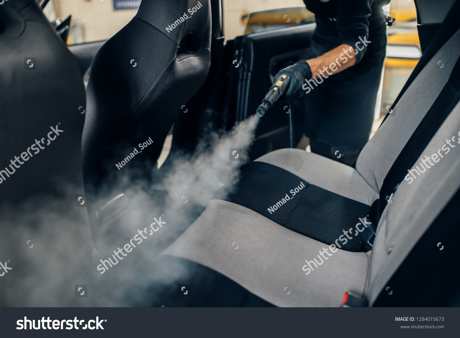 Carwash, worker cleans seats with steam cleaner #1284015673