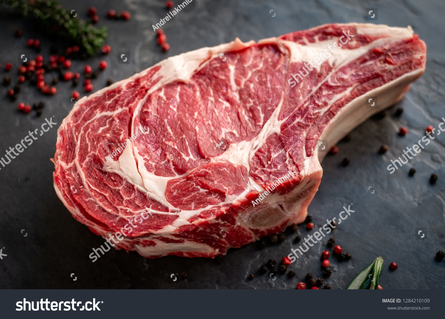 raw cowboy steak with seasonings on stone background, prime rib eye on bone #1284210109