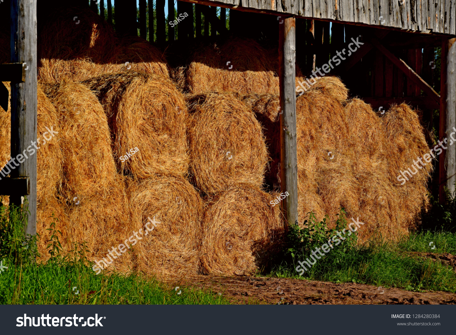 Dry baled hay bales stack, rural countryside straw background. Hay bales straw storage shed full of bales hay on agricultural farm. Rural land cowshed farm with hay straw bales stack under old shed #1284280384