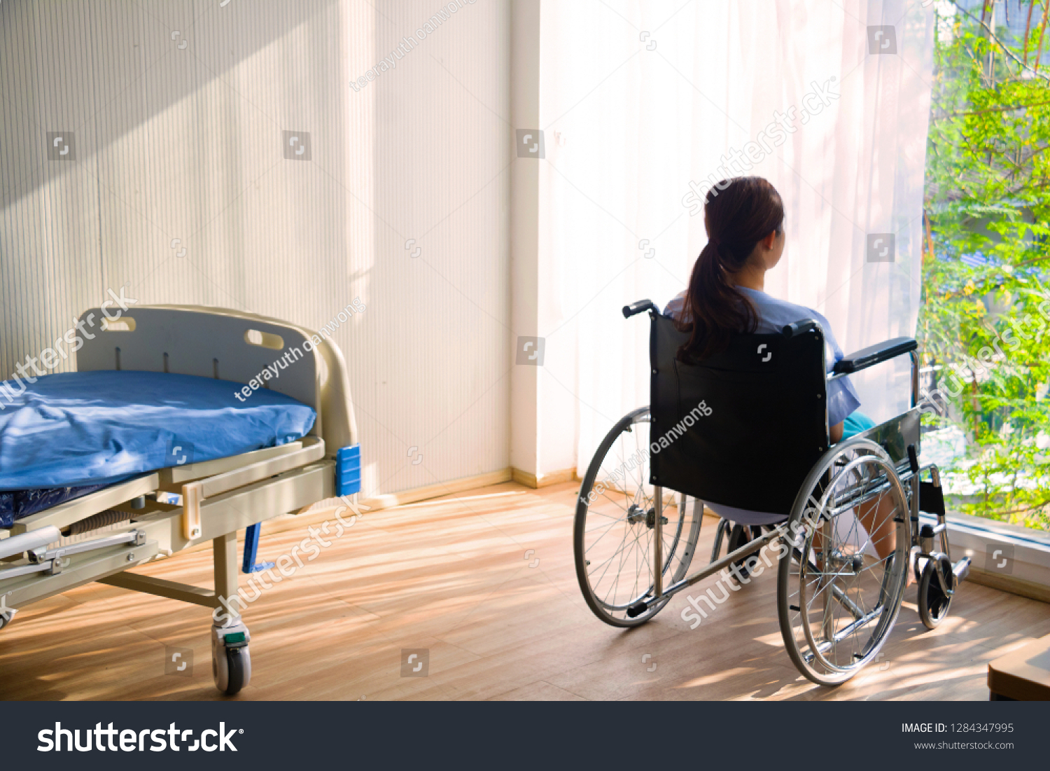 The woman sitting on wheelchair. She is see window with patient bed in hospital.disabled person lonely. Photo concept depression and Patient. #1284347995