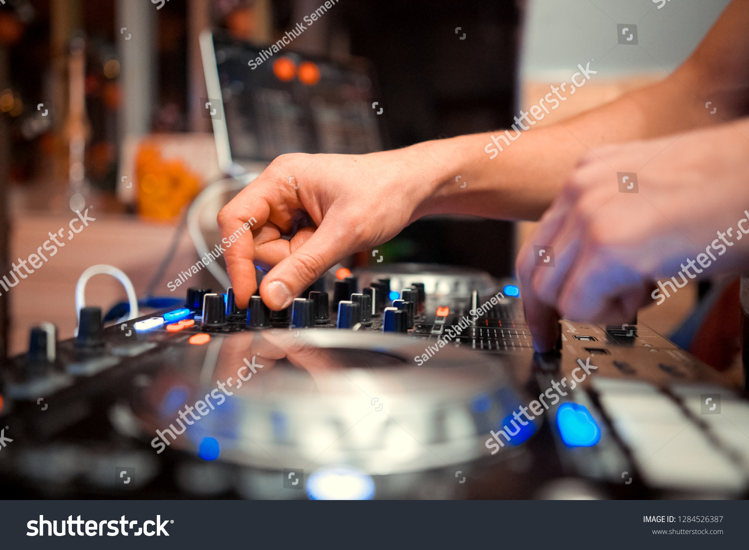 control DJ for mixing music with blurred people dancing at party in nightclub #1284526387