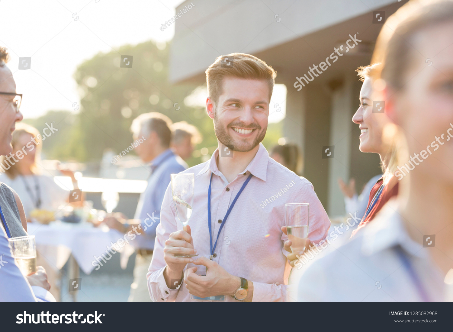 A group of attractive business colleagues enjoying a glass of champagne outside on a roof terrace in a restaurant or a bar. This could be a party, a convention, conference or a wedding event. #1285082968