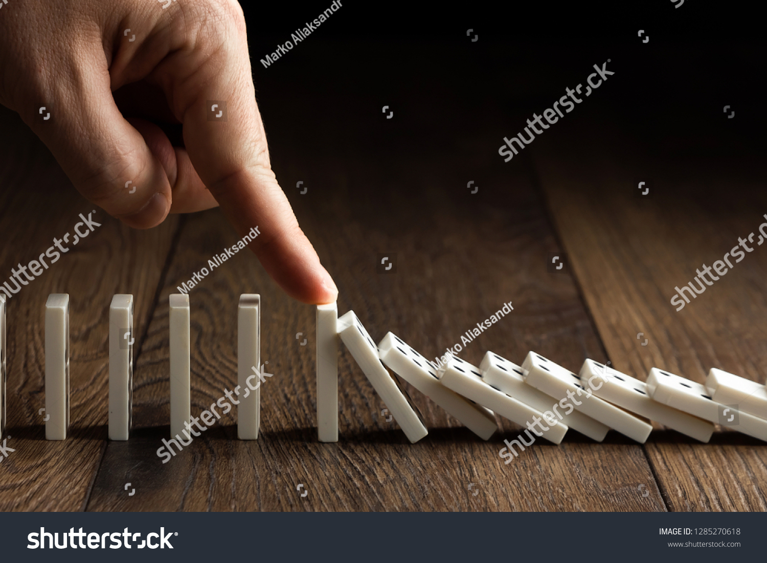 Creative background, Men's hand stopped domino effect, on a brown wooden background. Concept of domino effect, chain reaction, risk management, copy space. #1285270618