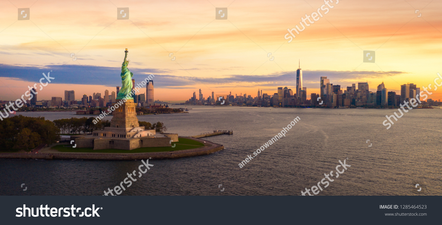 Liberty statue in New York city with manhatttan background and sunset, New York, USA #1285464523