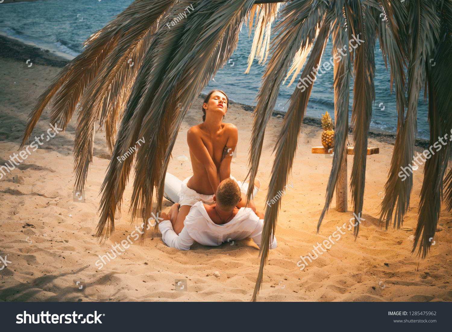Sensual. Attractive couple having sex on the beach. Sex on beach concept. Couple full of desire have sex on sand of seashore. Sensual lovers making love at seashore, sea on background. Vacation.  #1285475962