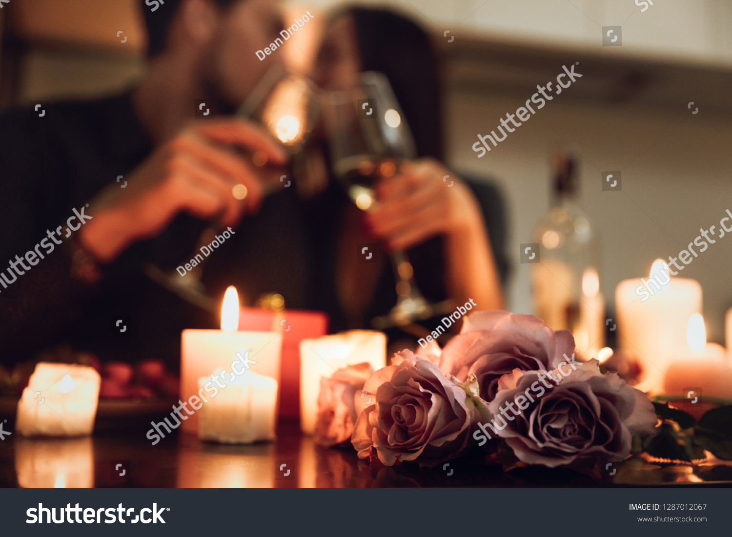Beautiful passionate couple having a romantic candlelight dinner at home, drinking wine, toasting #1287012067