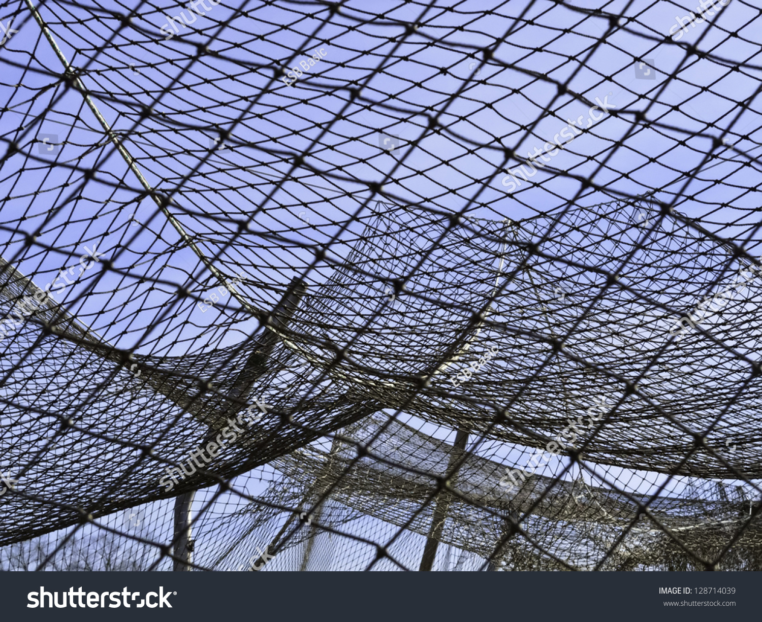 Complexities of practice: Part of netting over batting cage by baseball field on campus of community college #128714039