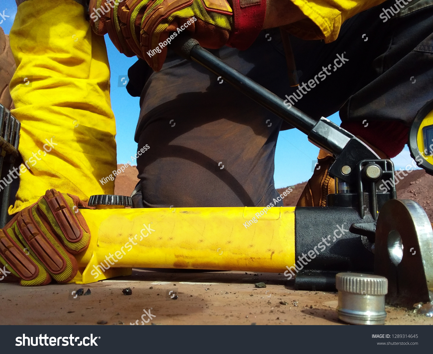 Rope access technician engineer worker hand holding pushing pull tester handle while testing pulling lifting lug load prior to lifting heavy loads construction mine site, Perth, Australia  #1289314645