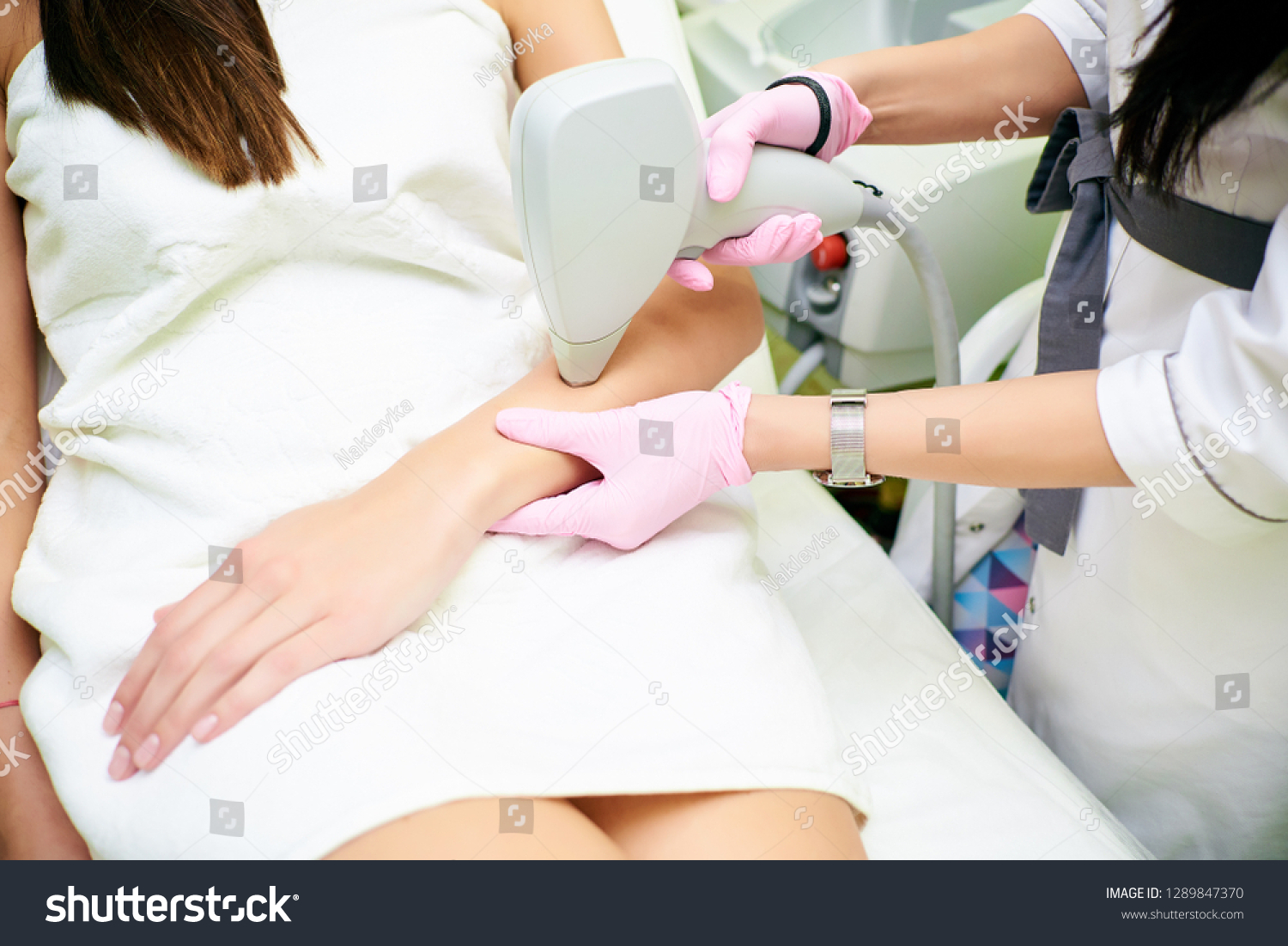 A cosmetologist carries out a procedure for laser hair removal from the body of a girl. Laser hair removal. Cosmology. Hand hair removal #1289847370