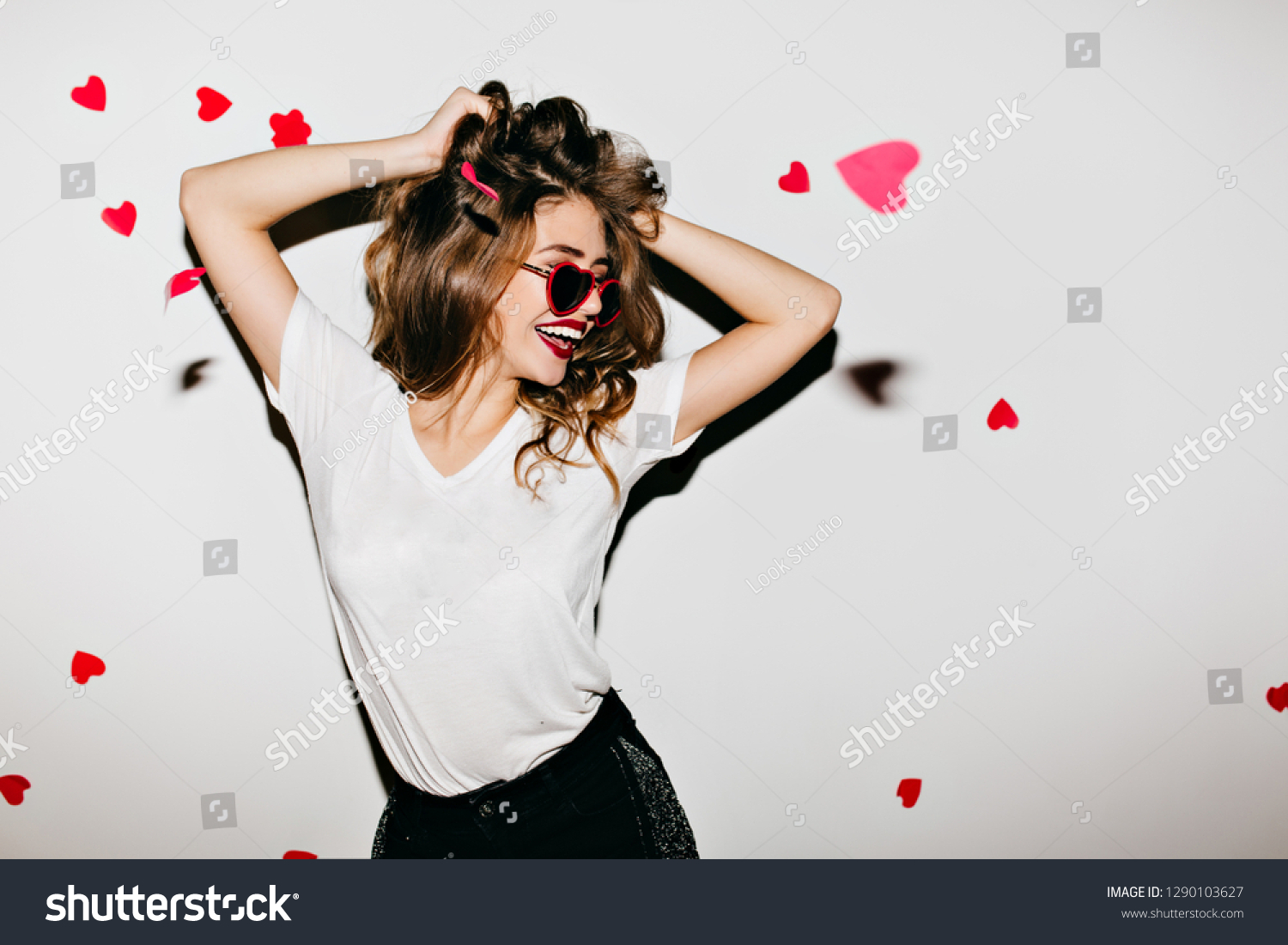 Slim european woman in glamorous sunglasses laughing on white background. Photo of good-looking girl playing with her wavy hair. #1290103627