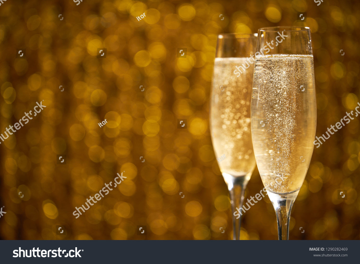 two glasses of champagne on golden stylish background with golden bokeh circles place for text #1290282469