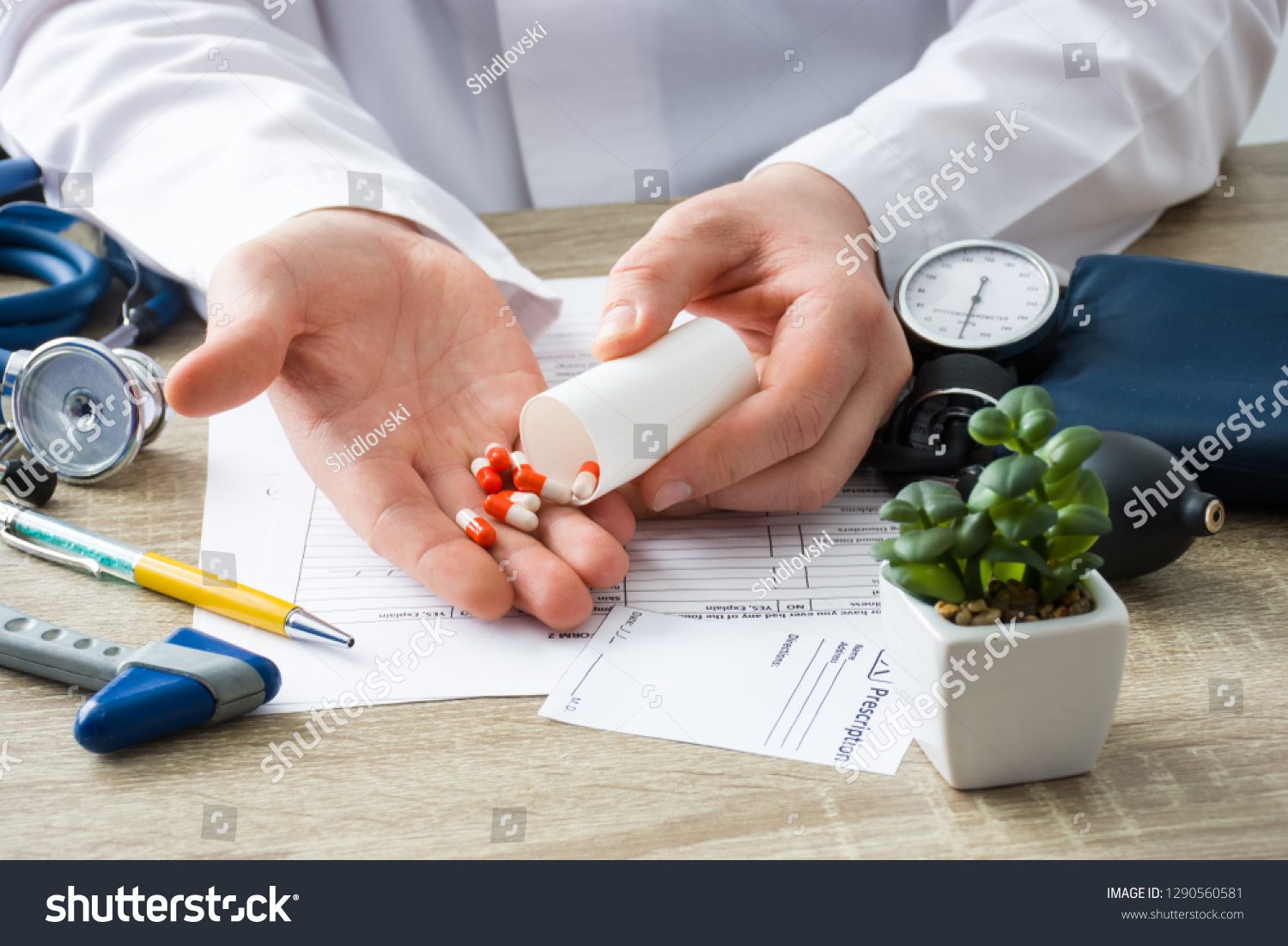 At doctors appointment physician shows patient capsules, which emptied into hand from container with focus on hand with drugs. Scene of prescription generic or OTC medications by doctor on visit #1290560581