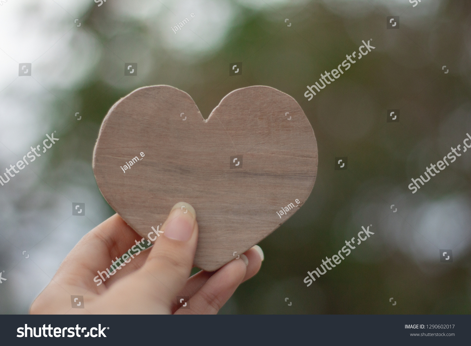Woman Hand holding wood heart on blurred green background,love valentine's day concept. #1290602017