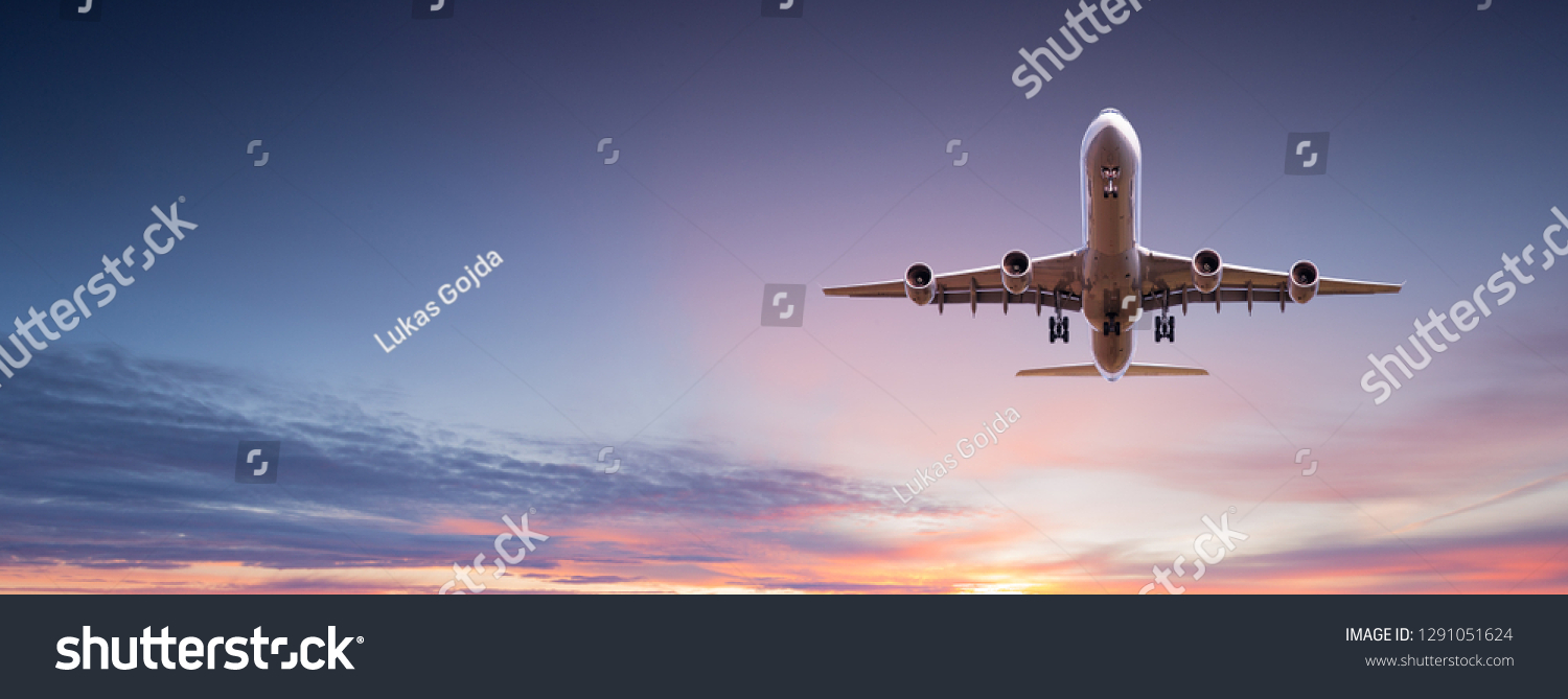 Commercial airplane jetliner flying above dramatic clouds in beautiful sunset light. Travel concept. #1291051624