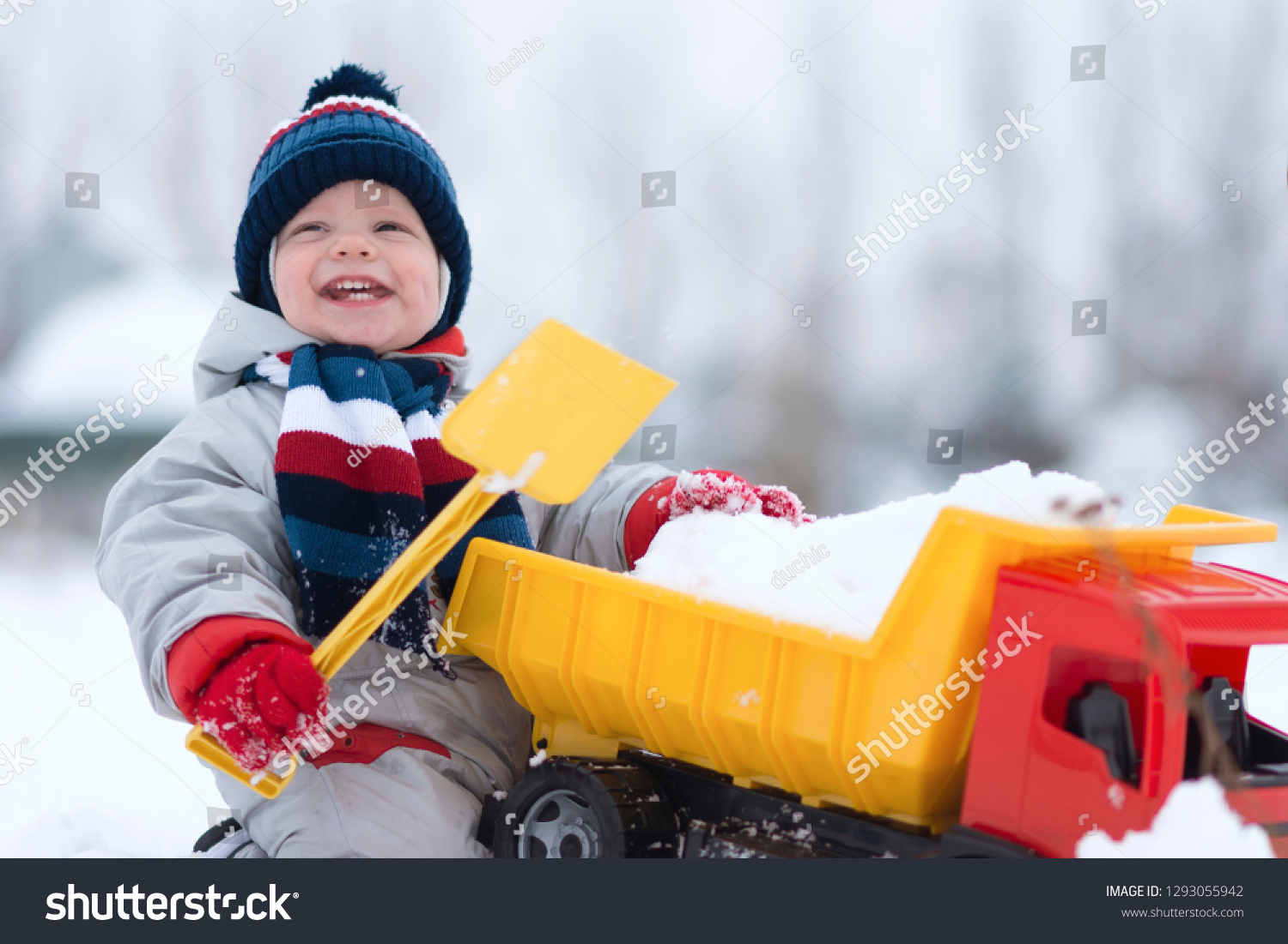 little baby boy playing with his favourite toy at the snowtime. A kid 15-23 month enjoy playfull,spending time in snow. A toddler  and his plastic truck at the winter games. Kids and toys concept #1293055942