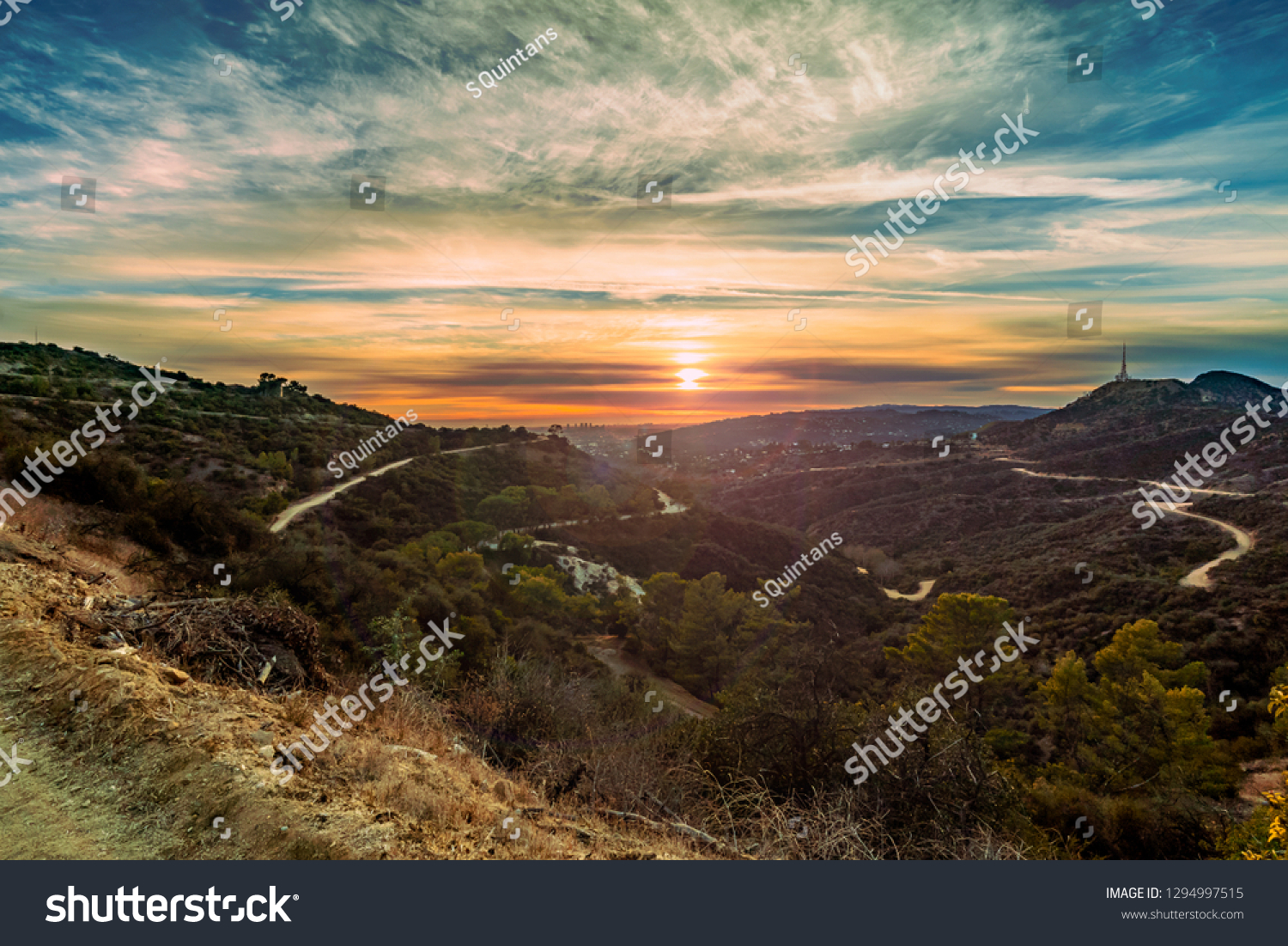An orange sunset view across the horizon between hills and mountains from a distant mountain top view in Los Angeles, California. #1294997515