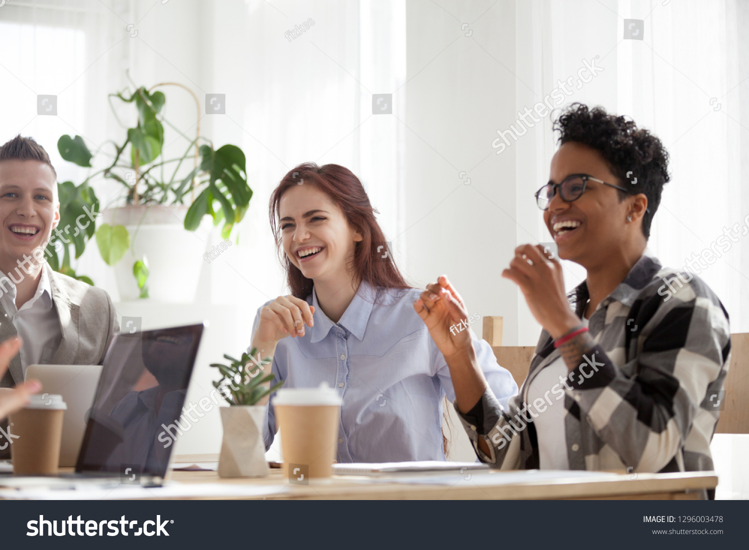 Happy joyful diverse business people laughing at funny joke talking at work break, cheerful corporate team office workers multi-ethnic young coworkers having fun engaged in teambuilding activity #1296003478