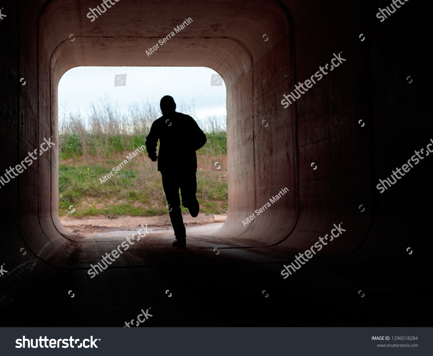 man running through dark tunnel escaping #1296518284