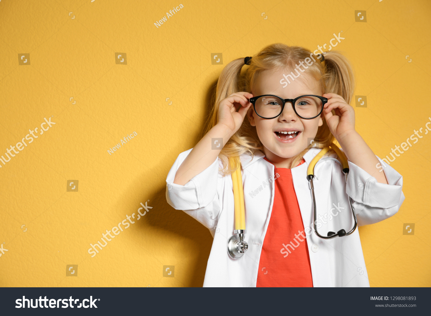 Cute child in doctor coat with stethoscope on color background. Space for text #1298081893