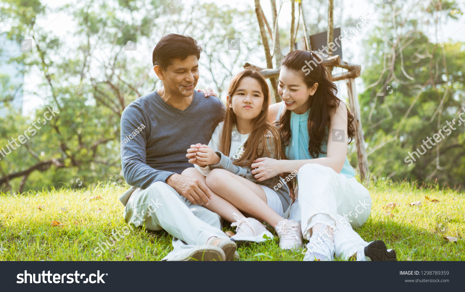 Happy parents and daughter having fun in the park #1298789359