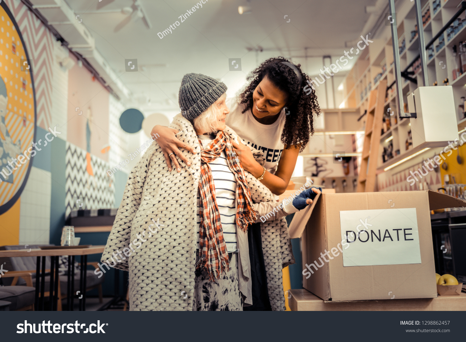 You need it. Nice joyful woman smiling while giving her old coat to a pleasant aged woman #1298862457