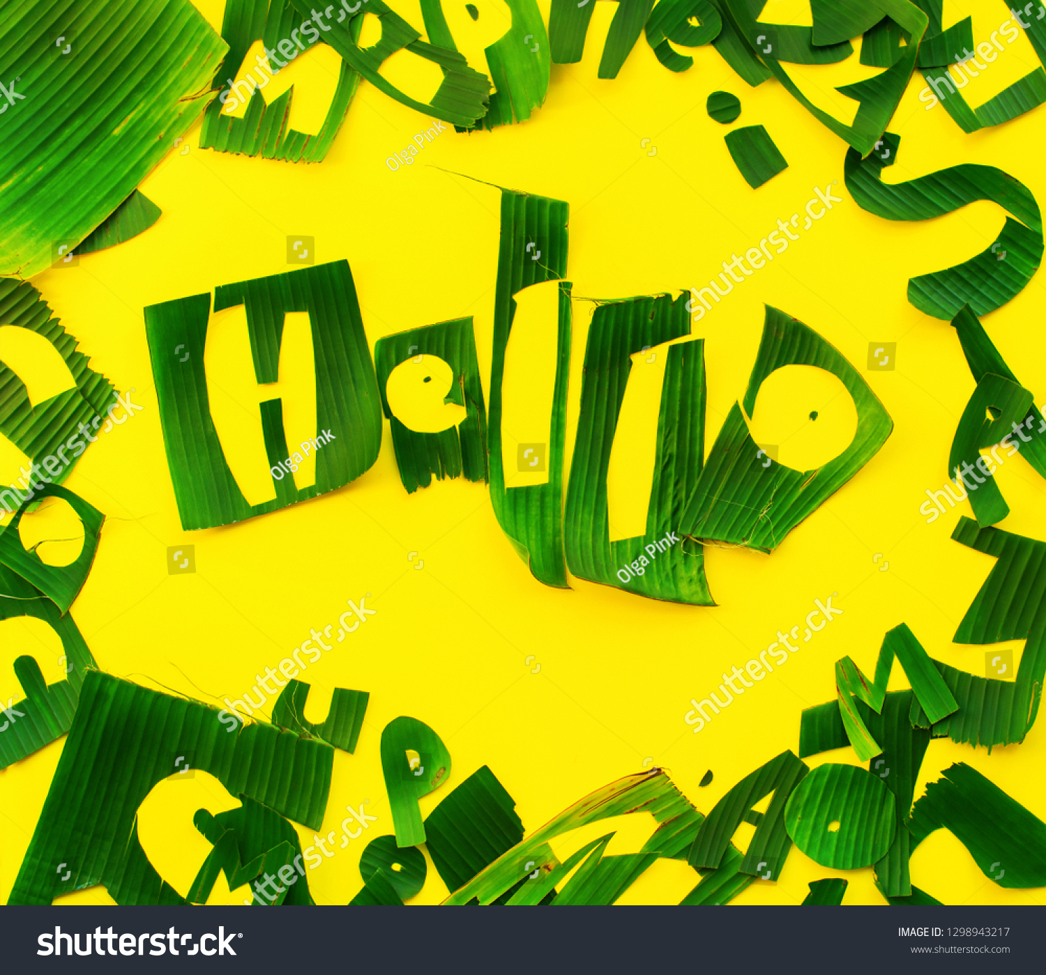 Word HELLO letters from green tropical palm leaves on yellow textured background. Original handmade idea from natural material for summer design and needlework #1298943217