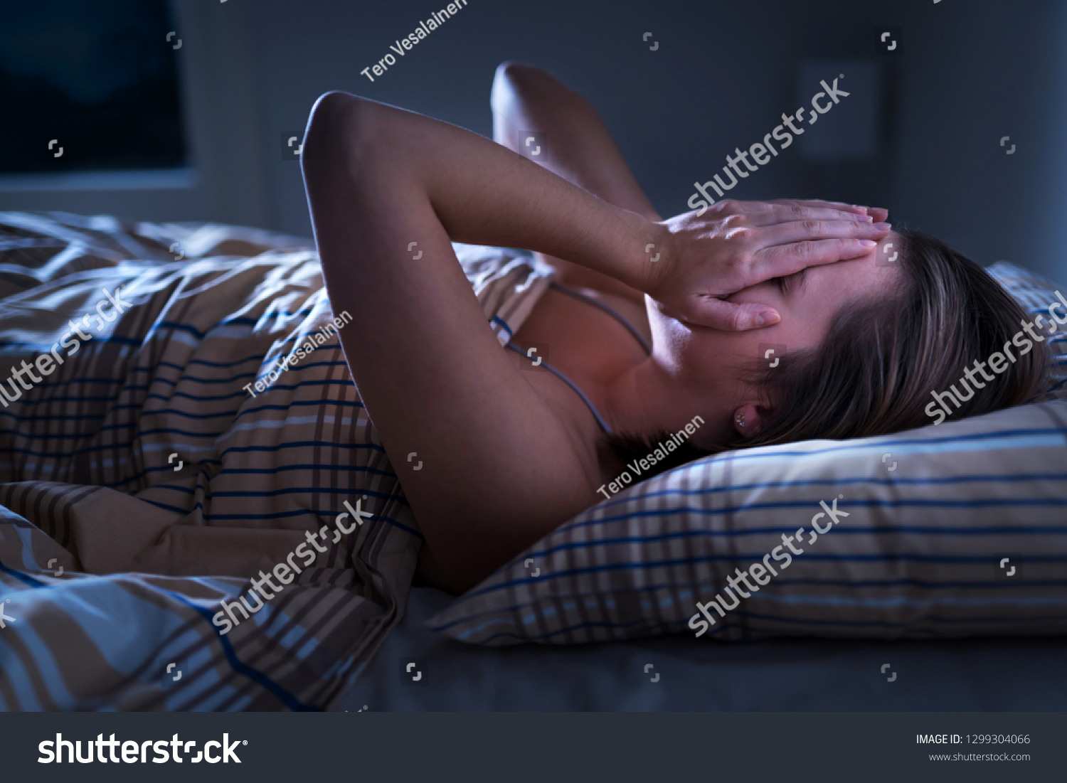 Insomnia, sleep apnea or stress concept. Sleepless woman awake and covering face in the middle of the night. Lady can't sleep. Nightmares or depression. Suffering from headache or migraine.  #1299304066