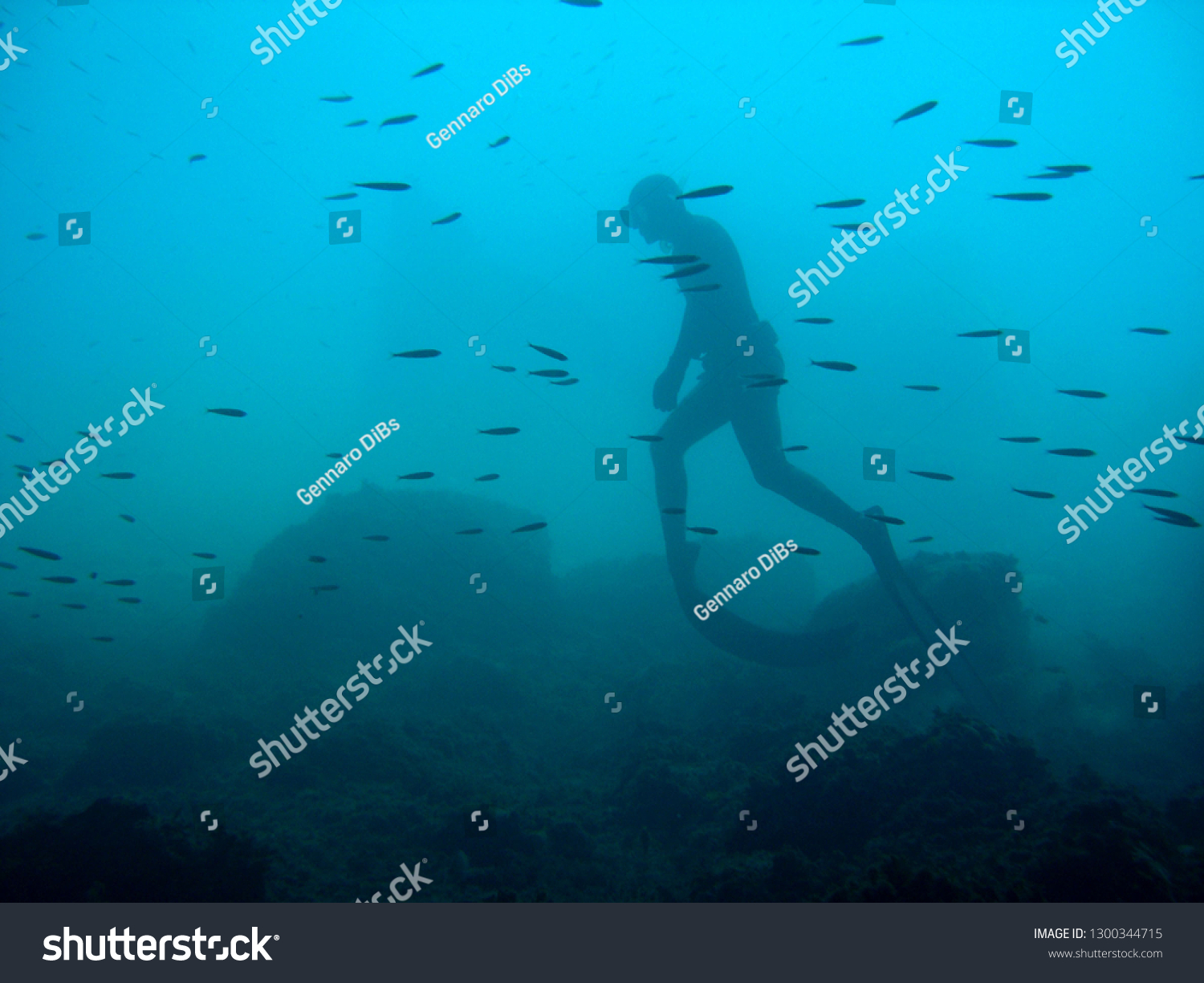 man in immersion freediving into blue of a submarine cave #1300344715