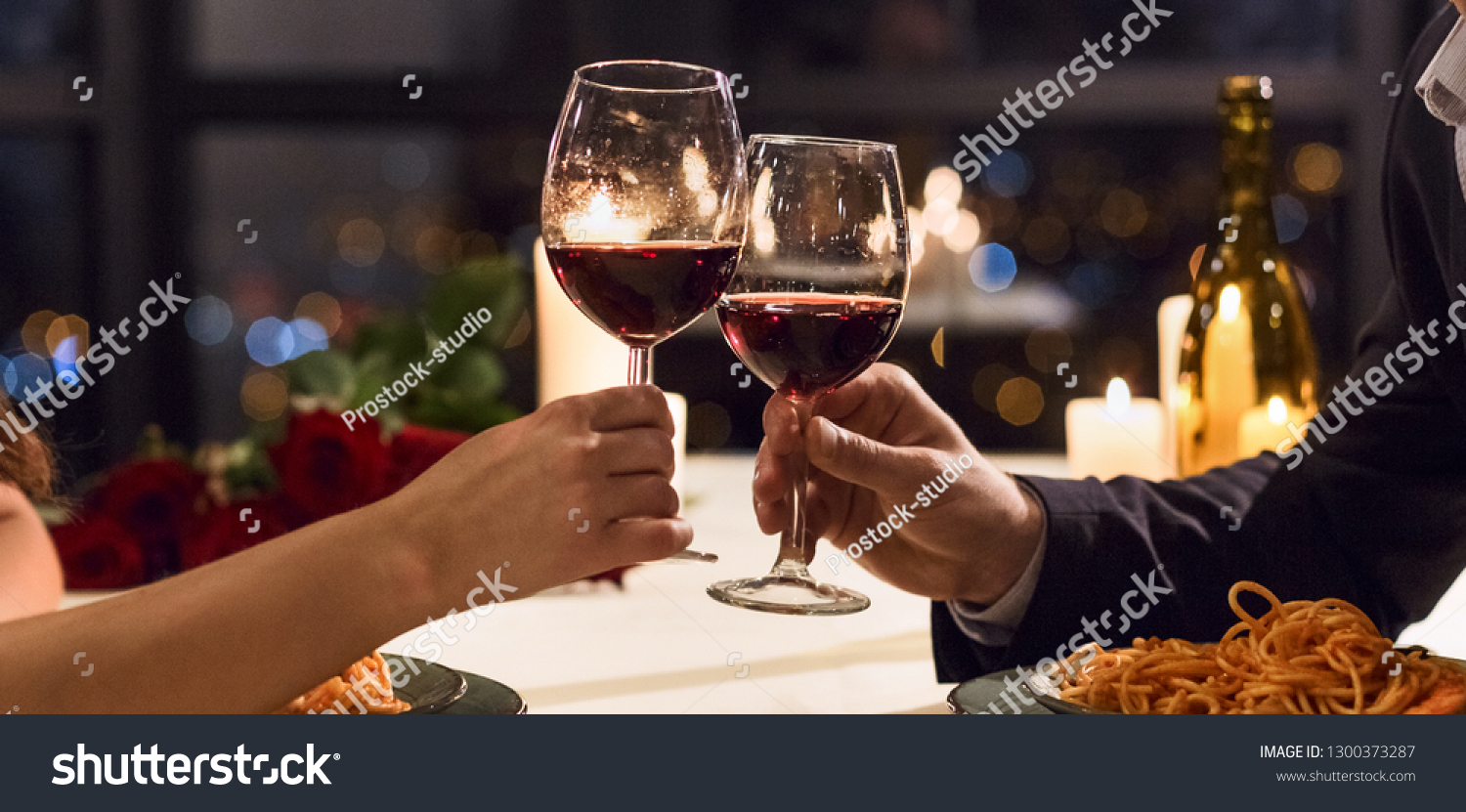 Hands holding glasses of wine on restaurant background. Let's have a toast concept #1300373287