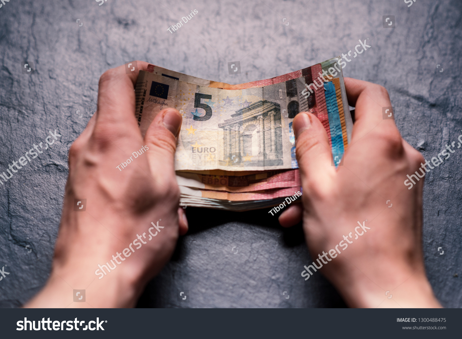 Hand´s of young man holding a money. Banknotes on a stone background. Euro money bank notes of different value. European currency - Euro. Bills of money. Man holding a bills of money.  #1300488475